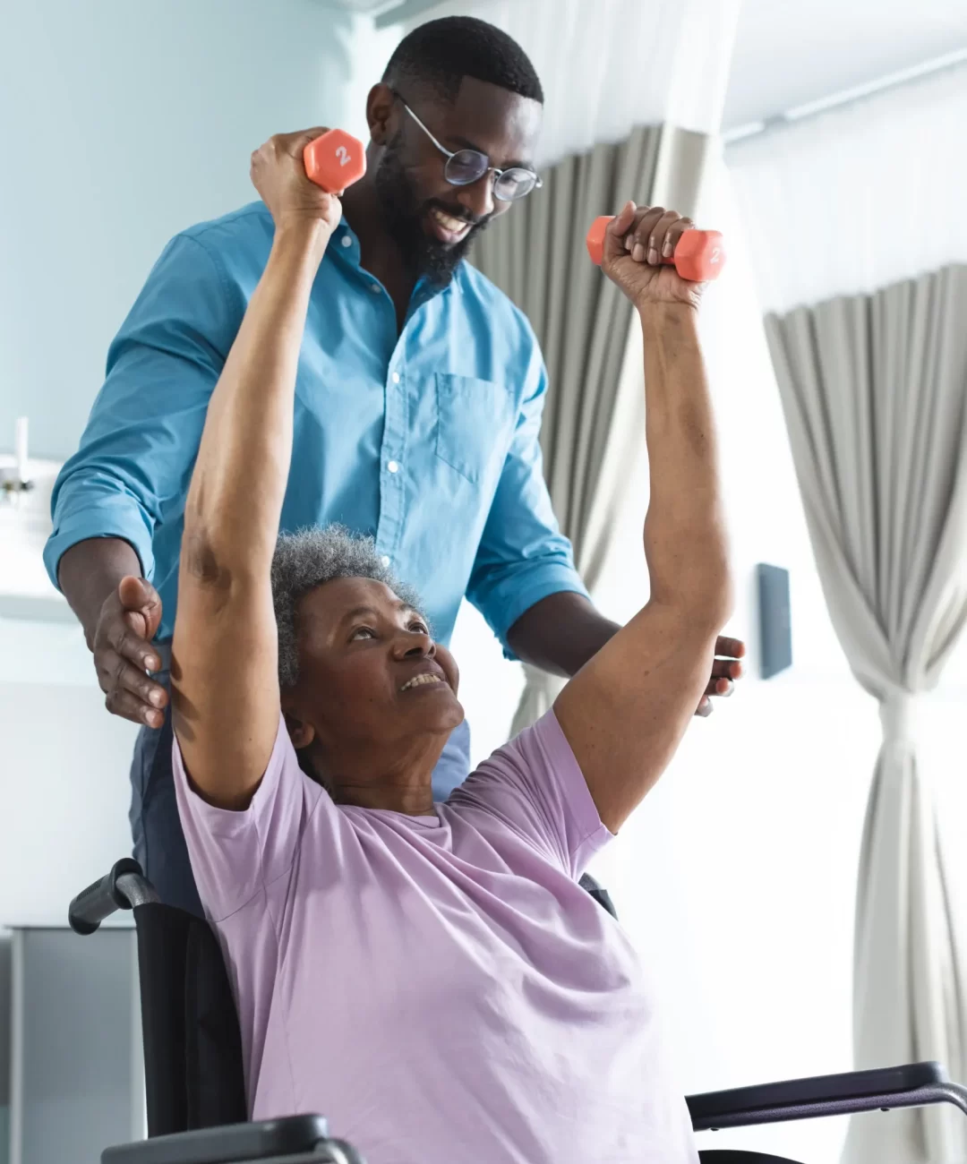 african-american-senior-woman-exercising-with-weights-male-doctor-advising-hospital-room